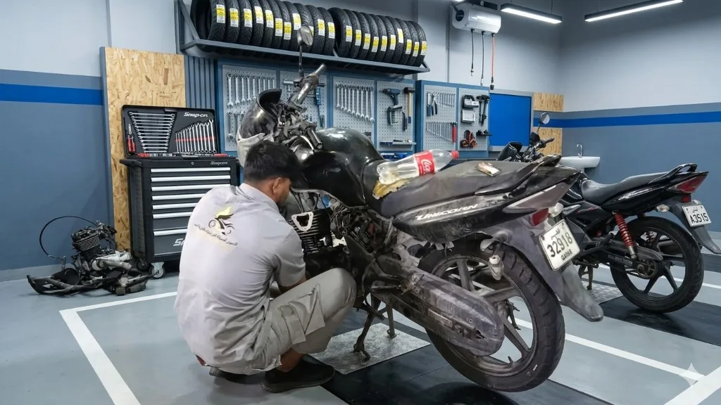 Mechanic servicing a delivery motorcycle in Al Nousour garage